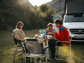 Freunde sitzen an einem Campingtisch im Grünen beim Estland Camping.